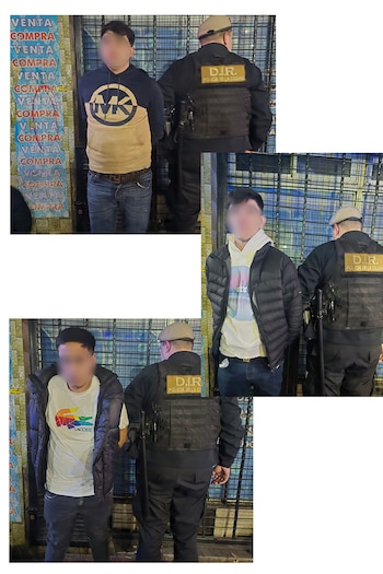 Un hombre con el rostro pixelado es detenido por un oficial de la Policía de la Ciudad, que lleva un chaleco táctico. Se ve un enrejado y carteles de "VENTA COMPRA"