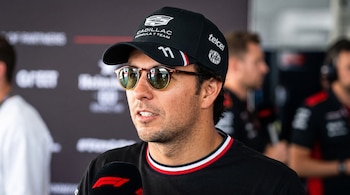 Sergio Pérez con gafas de sol y gorra negra con logotipos frente a un micrófono de Fórmula 1.