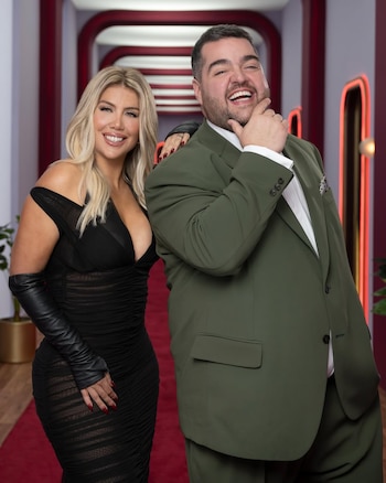 Wanda Nara, con vestido negro escotado y guantes de cuero, junto a Darío Barassi, quien viste un traje verde oliva, posan sonrientes sobre una alfombra roja