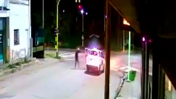 Vista nocturna de un taxi blanco en llamas o con humo espeso en una intersección de Bahía Blanca, con el conductor de pie cerca y alejándose