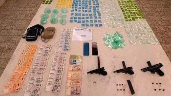 Drogas en bolsas de colores, fajos de pesos argentinos, tres armas de fuego, dos cargadores, dos teléfonos celulares y dos bolsos sobre una superficie
