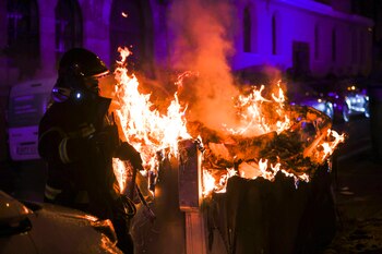 Un policía ante un contenedor ardiendo en la calle Ferraz, en Madrid, en una nueva jornada de protesta contra la amnistía celebrada este viernes en la capital. EFE/Javier Lizón