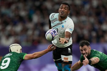 El fiyiano Joji Nasova pasa el balón ante el irlandés Hugo Lenox en los cuartos de final del torneo de rugby sevens de los Juegos Olímpicos de París, el jueves 25 de julio de 2024, en Saint-Denis, Francia. (AP Foto/Tsvangirayi Mukwazhi)
