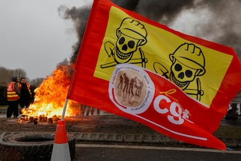 Una bandera ondea frente a una hoguera mientras los trabajadores franceses de la energía en huelga se reúnen en un bloqueo de carreteras cerca de la refinería de TotalEnergies en Gonfreville-L'Orcher, cerca de Le Havre (Reuters)