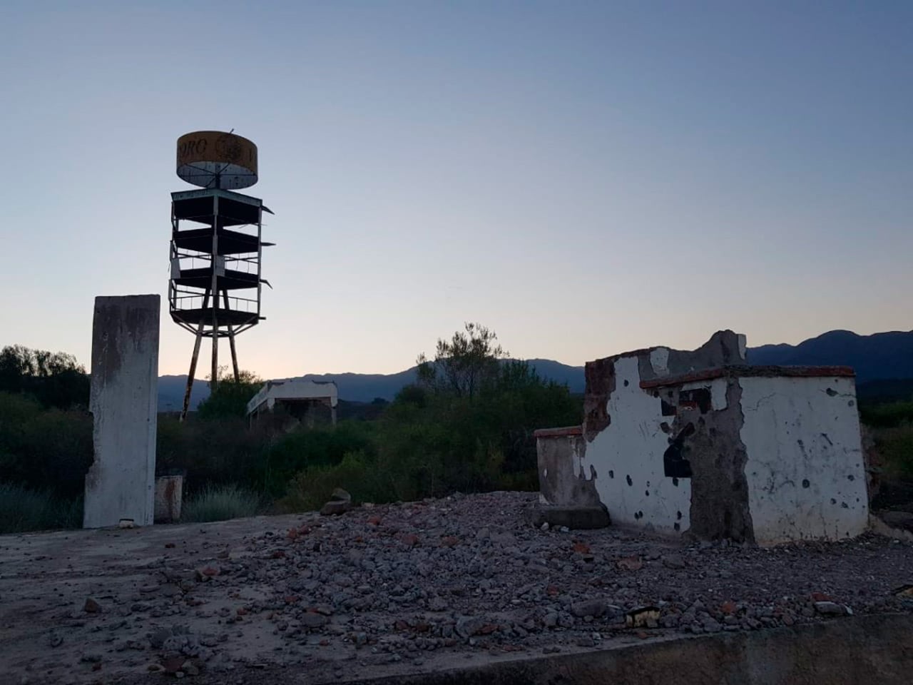 Una torre en ruinas y estructuras derrumbadas marcan el desolador paisaje del Autódromo General San Martín de Mendoza, mostrando el paso del tiempo y el abandono