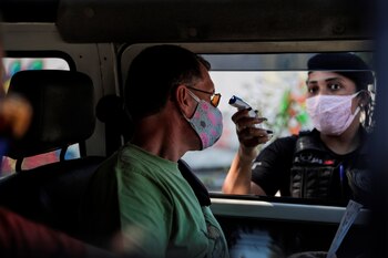 Un agente de seguridad del ayuntamiento de la ciudad de Niterói toma la temperatura de un hombre en Niterói, Río de Janeiro (EFE)