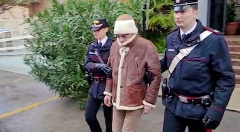 En esta imagen tomada de un video difundido por el cuerpo de Carabinieri de Italia el lunes 16 de enero de 2023, el capo de la mafia Matteo Messina Denaro, al centro, sale del cuartel de policía luego de ser arrestado en una clínica privada en Palermo, Sicilia, después de permanecer prófugo durante 30 años. (Carabinieri via AP/Archivo)