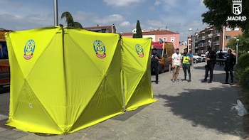 Carpa amarilla de SAMUR con logotipo, junto a una ambulancia y varios agentes de policía en una calle de Madrid durante un operativo diurno
