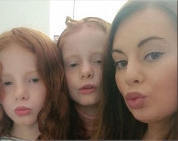 Primer plano de una mujer adulta con cabello oscuro y dos niñas pelirrojas, aparentemente gemelas, todas haciendo una pose de labios fruncidos