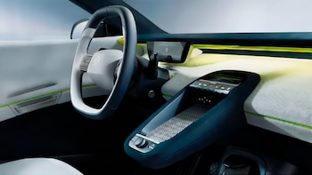 Interior de un automóvil con volante de dos tonos con el logotipo de Volkswagen, tablero claro con detalles verdes y consola central flotante