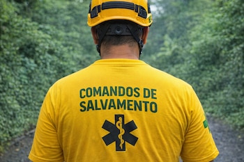 Vista trasera de un socorrista de Comandos de Salvamento vistiendo una camisa amarilla y un casco del mismo color, con el logo visible en la espalda.
