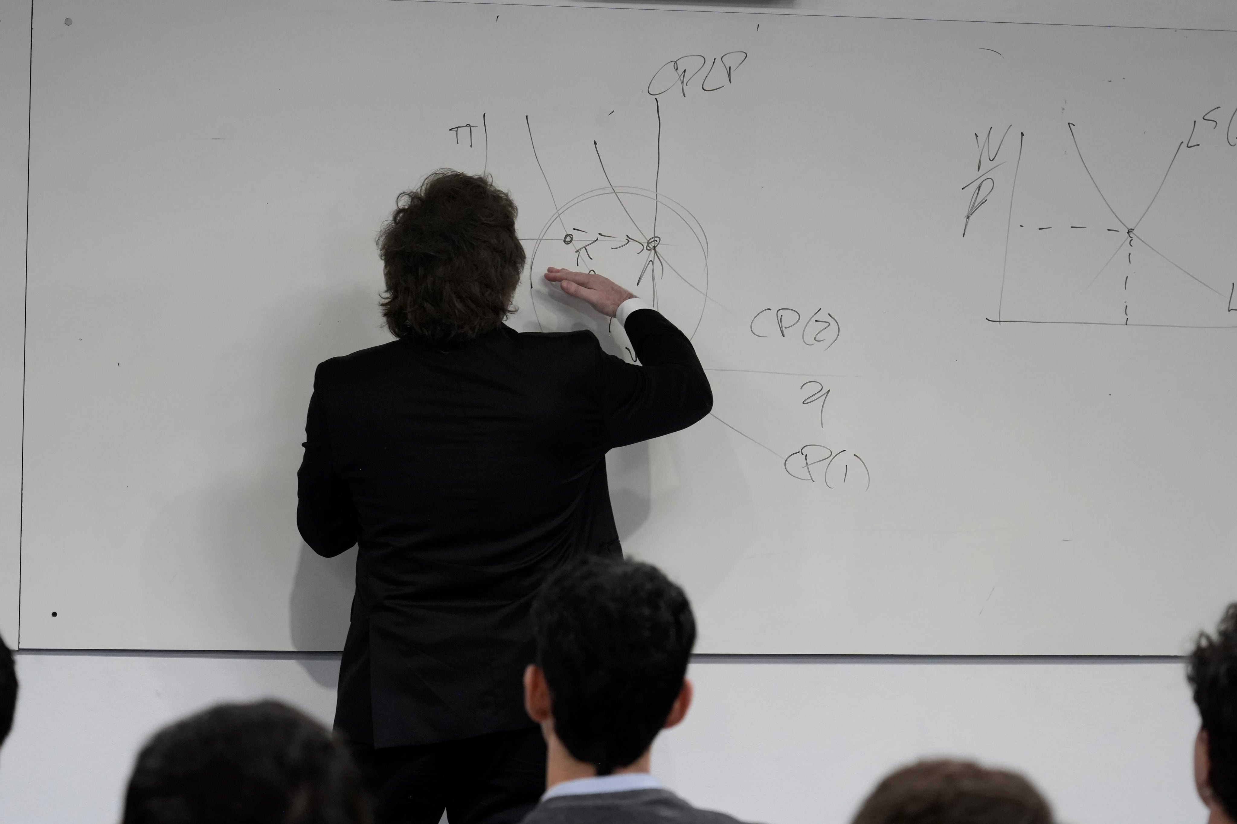 Javier Milei escribe en el pizarrón ante la atenta mirada de los alumnos