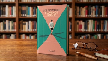 Un libro de tapa dura “Los Nombres” de Florence Knapp con una portada verde y rosa y una persona de espaldas, sobre un escritorio de madera con gafas y un bolígrafo