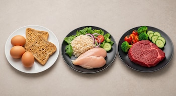 Vista superior de tres platos con alimentos: huevos y tostadas; pechugas de pollo crudas, arroz y ensalada; carne de res cruda y vegetales