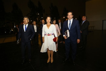 Roberto Sánchez y Keiko Fujimori, junto a otro hombre, caminan hacia adelante en un entorno oscuro. Sánchez viste traje azul, Fujimori un vestido blanco con cinturón floral