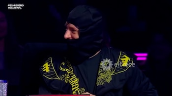 Persona con pasamontañas negro, chaqueta negra con tigres amarillos, sobre fondo oscuro. Logotipo de eltrece y textos #ESMISUEÑO #SEMIFINAL visibles