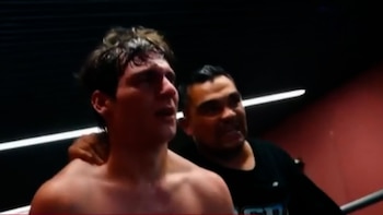 Pantalla de televisión dividida. Izquierda: hombre siendo entrevistado en un gimnasio. Derecha: dos hombres abrazándose en un ring de boxeo