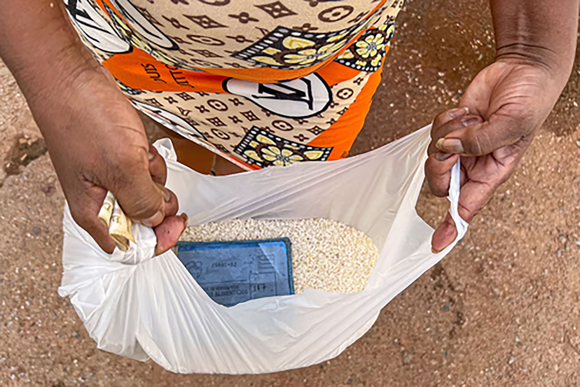 Una persona sostiene una bolsa con arroz y una libreta de racionamiento en Cuba (Food Monitor Program)