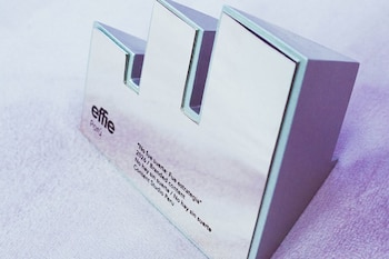 Un trofeo Effie Plata de forma geométrica y acabado brillante, con la inscripción "Effie Perú" y "No fue suerte: Fue estrategia"