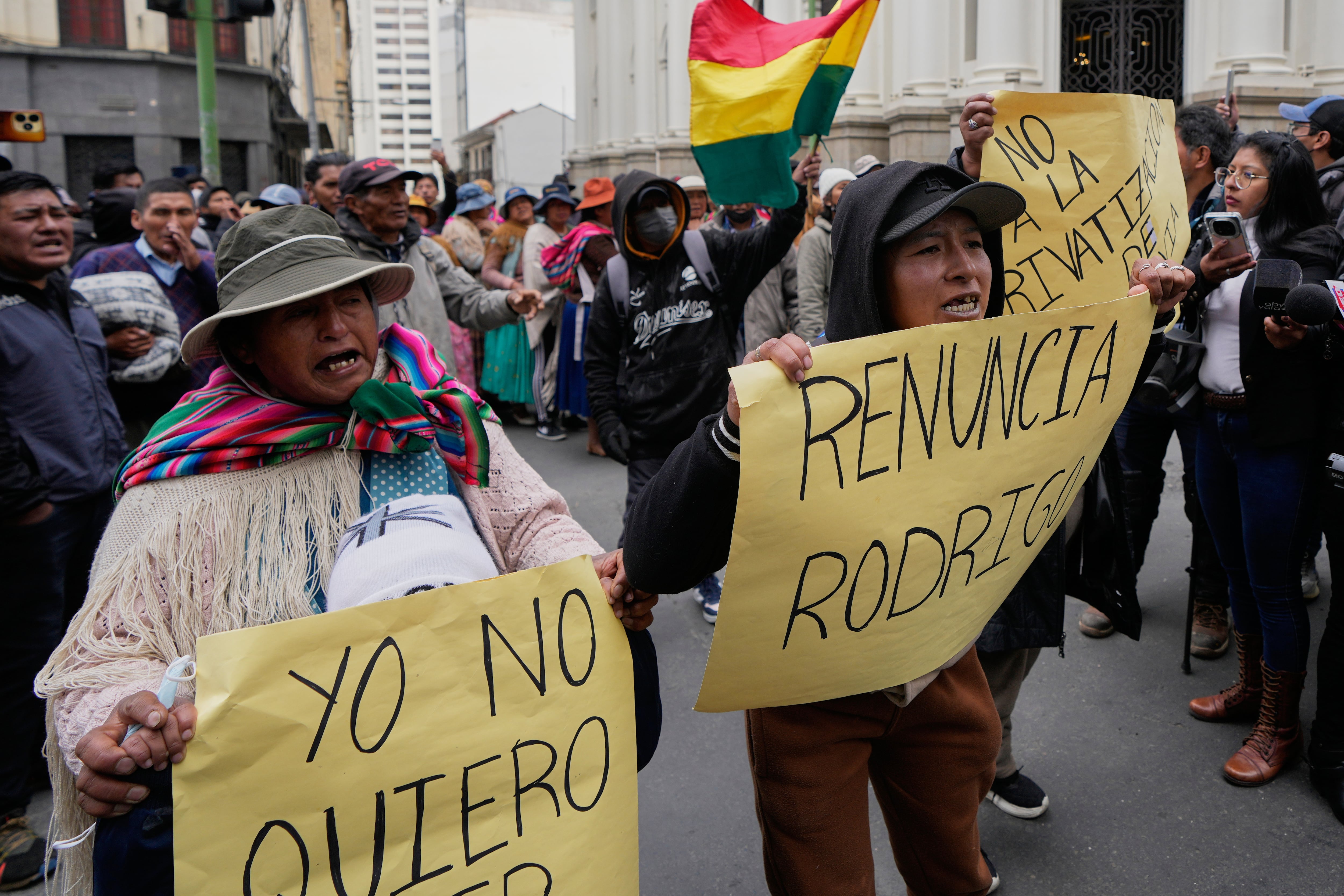 Manifestantes antigubernamentales sostienen pancartas en las que se lee