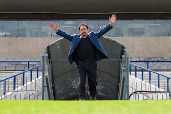 Hugo Sánchez camina hacia el campo con los brazos levantados al salir del túnel de acceso en un estadio de fútbol