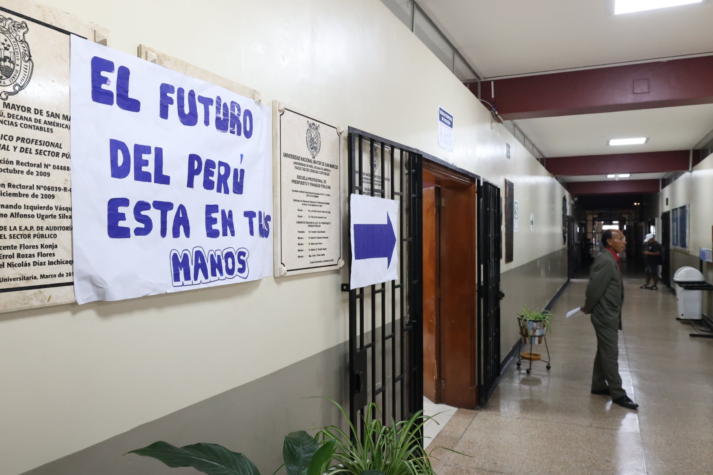 Un hombre observa el pasillo de la Universidad Nacional Mayor de San Marcos, donde se anuncian los módulos temporales de votación para las Elecciones 2026. (Paula Díaz Elizalde)