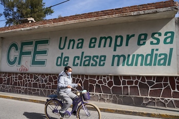 A person wearing a protective mask rides a bicycle past a Comision Federal de Electricidad (CFE) facility in Villa de Reyes, San Luis Potosi state, Mexico, on Tuesday, Jan. 19, 2021. Mexican President Andres Manuel Lopez Obrador has sought to clamp down on private competition to state-owned companies, saying in October he intends to protect the interests of state oil producer Petroleos Mexicanos and electricity firm Comision Federal de Electricidad. At the time, he accused foreign companies of ransacking the country.