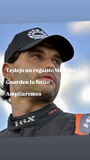 Primer plano de un hombre con gorra negra y buzo de competición negro y naranja, barba, aro dorado. Cielo azul y nubes. Texto superpuesto