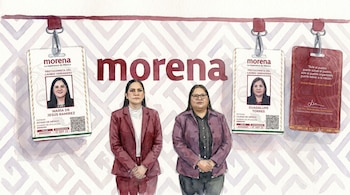 Dos mujeres con traje frente a credenciales de identificación del partido Morena, la palabra Morena y un fondo con patrones geométricos.