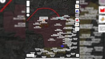 Captura de pantalla de un monitor de computadora mostrando un mapa satelital con zonas rojas y naranjas indicando órdenes de evacuación por un incendio