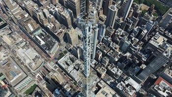 Vista aérea cenital de numerosos rascacielos, edificios de oficinas, calles con vehículos y una torre central prominente