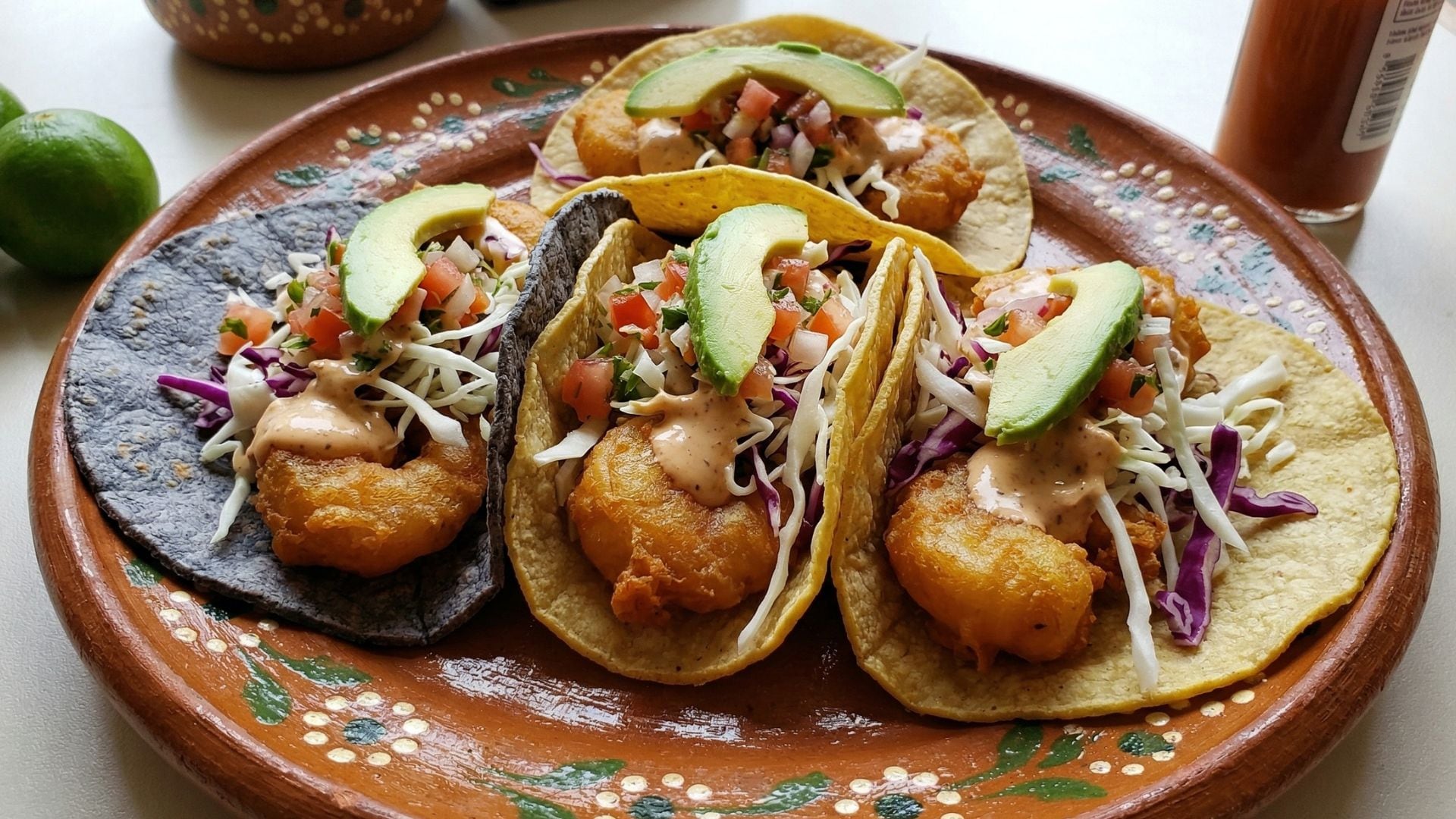 Una bandeja artesanal presenta cuatro tacos de camarón capeado, adornados con pico de gallo, repollo y aguacate, un plato esencial de la Cuaresma mexicana. (Gemini)