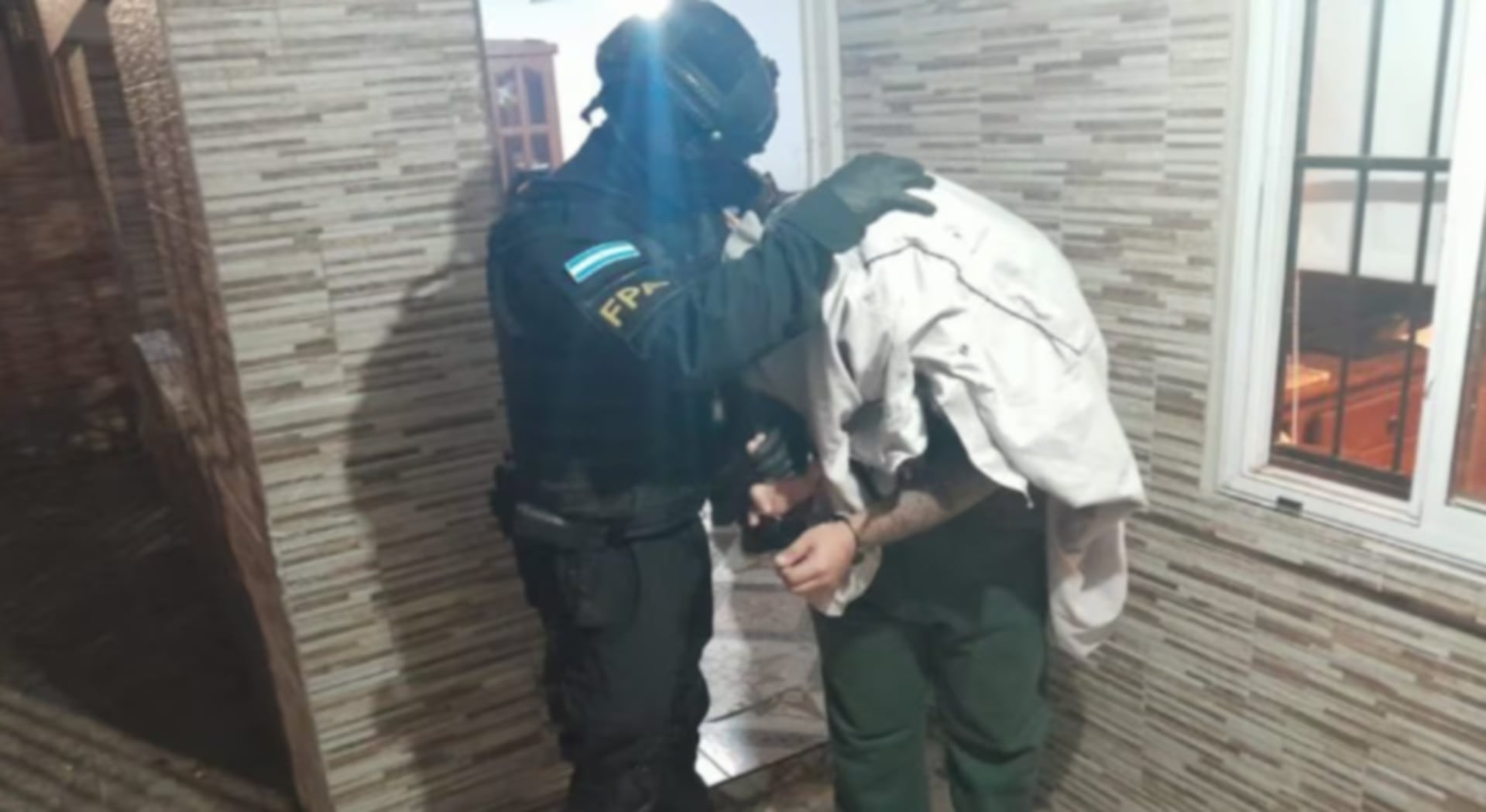 Un agente de la FPA detiene a un individuo en el marco de un allanamiento que desmanteló bunkers de drogas en la provincia de Córdoba (El Doce.tv)