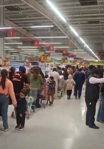 Nos corredores de um shopping movimentado há muitas pessoas empurrando carrinhos e prateleiras para os lados