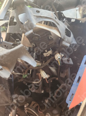 Partes internas de motocicleta: cables, conectores eléctricos, regulador de voltaje negro, piezas metálicas y fragmentos de carrocería azul y naranja
