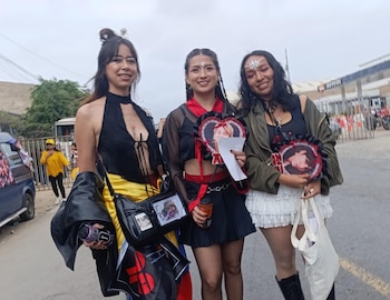 Tres jóvenes posan en la vía pública con vestimenta de color negro y abanicos decorados con fotografías