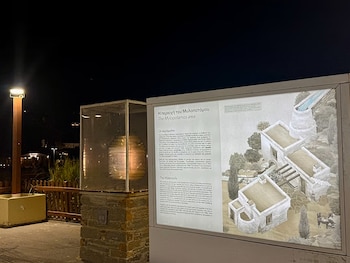 Un panel informativo con esquemas de molinos, una vitrina con una lente de faro e iluminación nocturna en el exterior