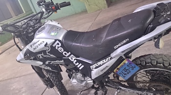 Motocicleta de color blanco y negro con la placa peruana 2435-SC y adhesivos decorativos sobre el tanque y la carrocería