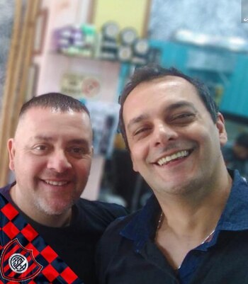 Martin Ortiz con un cliente cortando el pelo en su peluqueria