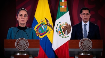 Una mujer y un hombre frente a dos atriles con el escudo de México, con las banderas de Ecuador y México detrás.