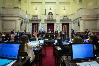 Vista elevada de un recinto legislativo semicircular con personas sentadas en bancas frente a computadoras y pantallas electrónicas