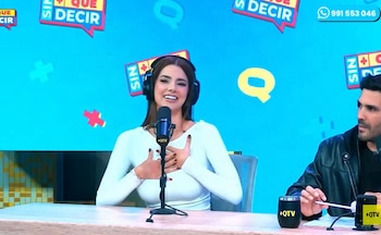 Suheyn Cipriani sentada en un estudio de televisión con auriculares y micrófono, con un hombre parcialmente visible a la derecha. Fondo azul con logos
