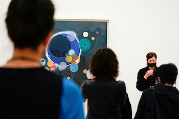 Los visitantes miran pinturas del