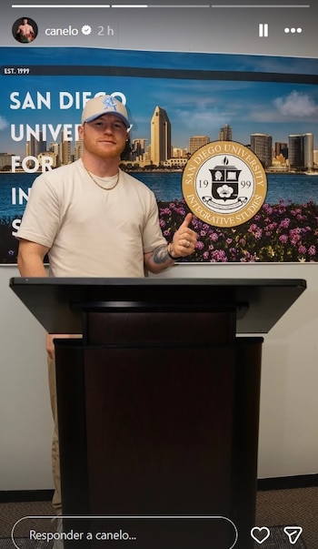 Saúl "Canelo" Álvarez, de pie detrás de un podio, da un pulgar arriba frente a un banner de la San Diego University for Integrative Studies