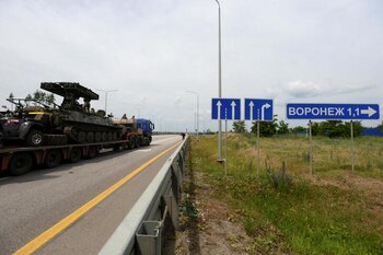 Un camión transportando un vehículo militar avanza por la autopista M-4 junto a un cartel que anuncia el acceso a Voronezh, Rusia (REUTERS)
