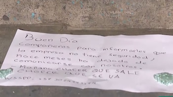 Una hoja de papel arrugada con un mensaje manuscrito en tinta negra y trozos de cristal verde roto, sobre una superficie de cemento gris