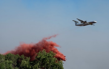 Un avión cisterna descarga agua y tierra mientras combate incendios forestales en Arès, en el oeste de Francia, el viernes 24 de julio de 2026 (AP/Caroline Blumberg)