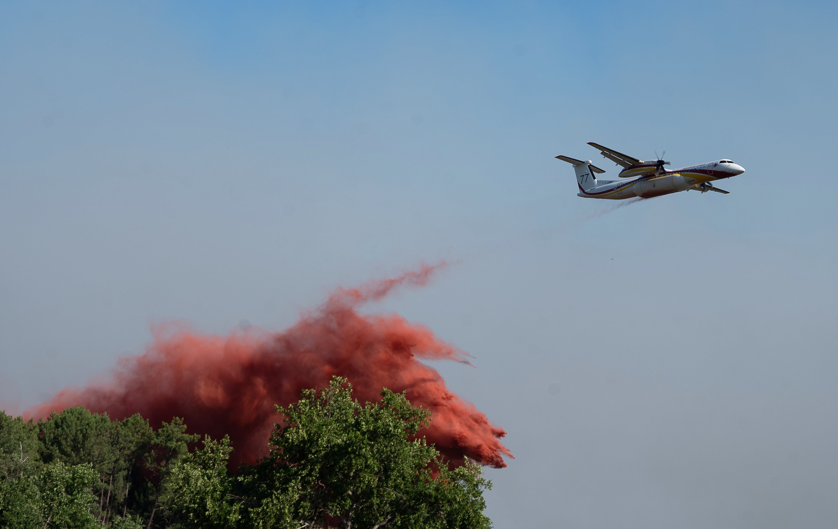 Un avión cisterna descarga agua y tierra mientras combate incendios forestales en Arès, en el oeste de Francia, el viernes 24 de julio de 2026 (AP/Caroline Blumberg)