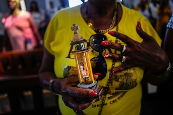 Una mujer sostiene una estatuilla de la Virgen de la Caridad del Cobre durante una misa en el santuario de El Cobre, Cuba, el domingo 11 de febrero de 2024. (AP Foto/Ramón Espinosa)
