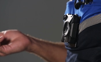 Una cámara corporal de color negro fijada al uniforme azul de un agente de policía